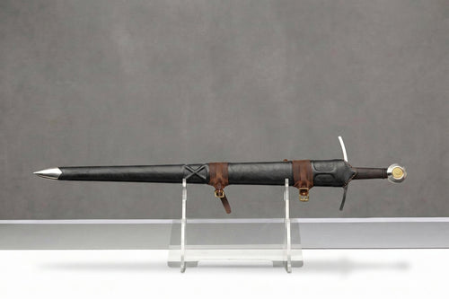 Goldwarden Arming Sword: Black leather sword scabbard with brown straps and hilt on clear stand, grey background