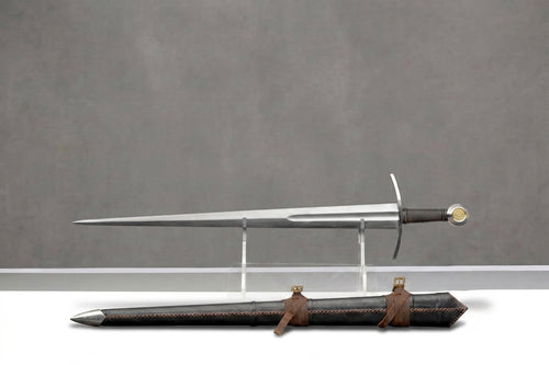 Goldwarden Arming Sword: Silver arming sword with dark grip, gold pommel, on clear stand, leather scabbard, grey background
