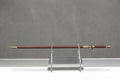 Needle - Arya Stark's Sword - Game of Thrones: Dark brown wooden sword scabbard with ornate gold fittings on clear stand, gray wall
