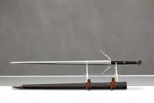 Wolf School Longsword - The Witcher 3 Inspired: Silver longsword with black grip and wolf pommel on clear stand, black leather scabbard below, grey background